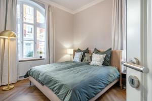 Schlafzimmer mit einem Bett mit grüner Bettwäsche und einem Fenster in der Unterkunft Apartment Villa Anna - Wohnung mit Stellplatz in Emden