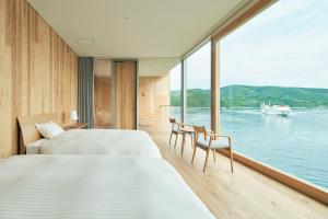 two beds in a room with a view of the water at Entô in Ama