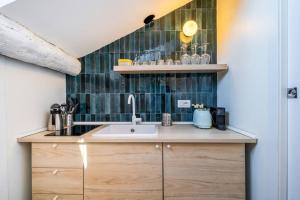 eine Küche mit einem Waschbecken und einer grünen Wand mit Fliesenböden in der Unterkunft Easylife - Grazioso monolocale in zona Buenos Aires in Mailand
