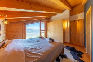 a bedroom with a large bed with a large window at Ciel Etoilé - Magnifique Chalet, 14 personnes - vue incroyable in Nendaz