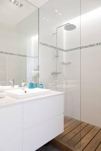 a white bathroom with a sink and a glass shower at Arc de Triomphe Apartment in Paris