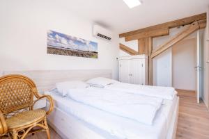 a bedroom with a white bed and a chair at Speicher Residenz Barth E3 App 11 in Barth