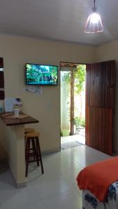a living room with a bed and a tv on the wall at Flores do Riacho in São Miguel dos Milagres