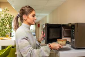 a woman is standing in front of a microwave at Hotel Aurena in Aurillac