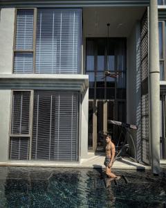マイカオビーチにあるBaan Maikhao pool villaの家の隣のプールに立つ男