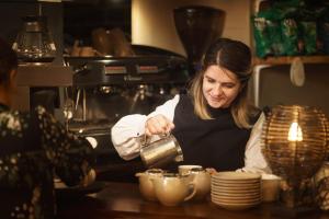 una donna in cucina che prepara tazze e piatti di Chapter House a Salisbury