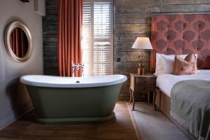 a bathroom with a bath tub next to a bed at The Chapter House in Salisbury