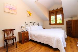 1 dormitorio con 1 cama blanca y 1 silla en Apartamentos El Retiro del Mirador by RetiroRural, en Arenas de San Pedro