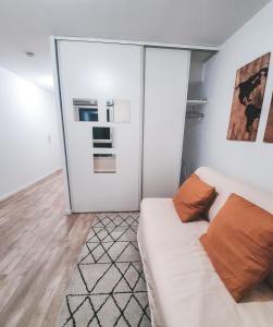 10 min de Paris Appartement touristique ou d'affaires في روسني-سو-بوا: غرفة معيشة مع أريكة بيضاء وباب زجاجي منزلق