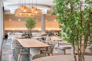 een restaurant met tafels, stoelen en bomen bij B&B HOTEL Lisboa Montijo in Montijo
