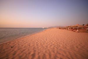 ein Strand mit Sonnenschirmen und Stühlen und das Meer in der Unterkunft Imperial Shams Abu Soma in Hurghada