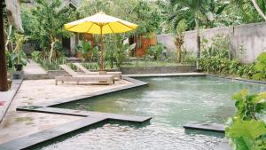 einen Pool mit Sonnenschirm und Stühlen im Hof in der Unterkunft Lullabi Lumbung Villa in Lajor