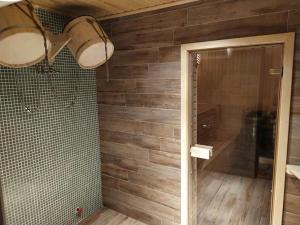 a bathroom with wooden walls and a shower with a glass door at Nino Ratiani's Guesthouse in Mestia