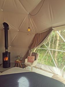 a room with a tent with a chair and a fireplace at Teapot Lane Glamping - Adults only in Sligo