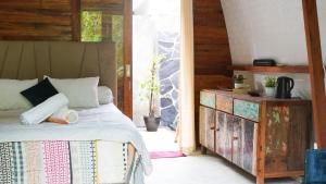 ein Schlafzimmer mit einem Bett und einer Holzkommode in der Unterkunft Lullabi Lumbung Villa in Lajor