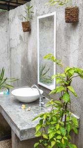 ein Badezimmer mit einem Waschbecken und einem Spiegel auf einer Ablage in der Unterkunft Lullabi Lumbung Villa in Lajor