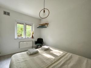 een slaapkamer met een bed met een stoel en een raam bij Modern natuurhuisje midden in het bos op de Veluwe - Beau Home in Otterlo