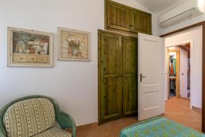 um quarto com uma porta verde e uma cadeira em Statzu Butzu em Costa Paradiso