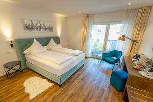 ein Schlafzimmer mit einem Bett, einem blauen Stuhl und einem Schreibtisch in der Unterkunft Landhaus Biewald in Göttingen