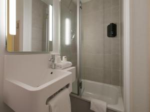 y baño blanco con lavabo y ducha. en B&B HOTEL Le Mans Nord 2, en Saint-Saturnin