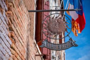 a sign on the side of a building next to a flag at Palazzo Marcello Hotel Al Sole in Venice