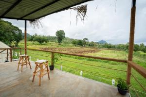 eine Veranda mit 2 Tischen und Blick auf ein Feld in der Unterkunft Cozy Farm Stay in Matale
