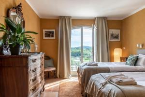 a bedroom with two beds and a large window at Domaine Rabiega - Vineyard and Boutique hotel in Draguignan