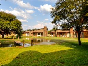 a building with a pond in front of it at Monomotapa Village @ Legend Golf and Safari Resort in Golders Green
