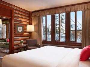 Schlafzimmer mit einem Bett, einem Stuhl und Fenstern in der Unterkunft Fairmont Jasper Park Lodge in Jasper