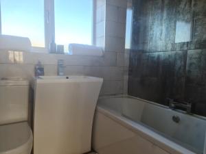 a bathroom with a tub and a toilet and a sink at Stunning 3 Bedroom Dutch barn cottage with parking in Stockton-on-Tees