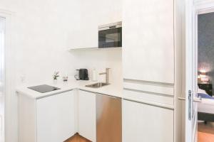 biała kuchnia ze zlewem i kuchenką mikrofalową w obiekcie Pink Grapefruit City Condo w Wiedniu