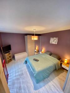 a bedroom with a large bed and purple walls at Agréable maison de ville avec parking gratuit in Corent