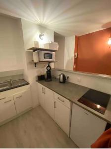 a small kitchen with white cabinets and a microwave at Studio hyper centre de Caen in Caen
