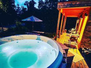 a bath tub sitting on a deck with an umbrella at Au Pré de Mukky in Andenne