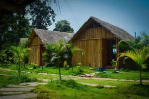 une maison en bambou avec un toit de chaume dans un jardin dans l'établissement Ibni Springs, à Madikeri