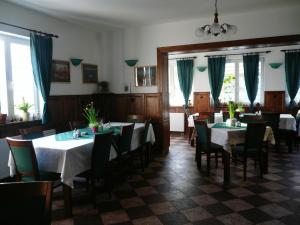 une salle à manger avec des tables, des chaises et des rideaux bleus dans l'établissement Penzion U Studánky, à Karlovy Vary