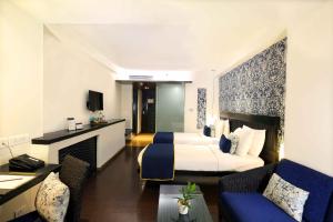 Mosaic Hotel, Noida في نويدا: غرفة فندقية بسريرين واريكة