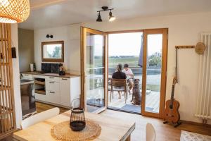 two people sitting at a table in a kitchen with a dog at Wohnwagon Paul - Autarkie erleben! - Tiny House in Oberschneiding
