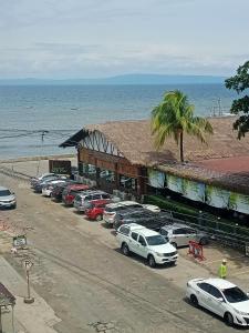 un edificio con coches aparcados en un aparcamiento junto al océano en Condotel DC MARINA SPATIAL FELINVEST en Dumaguete