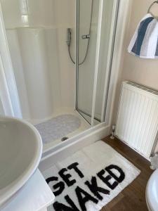 y baño con ducha y alfombra blanca. en Beautiful Butlins van, en Lincolnshire