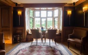 a dining room with a table and chairs and a window at Whatley Manor in Malmesbury