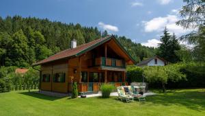 ein Blockhaus mit einer Veranda und zwei Stühlen im Hof in der Unterkunft Ferienhaus Rauscher in Sittersdorf