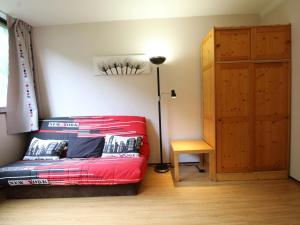 1 dormitorio con cama roja y lámpara de pie en Studio Flaine, 1 pièce, 4 personnes - FR-1-687-47, en Arâches-la-Frasse