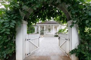 an archway leading to a house with a white gate at Cosy Cottage - The Inner Temple by StayVista with Outdoor jacuzzi, Steps from Mandwa Beach in Alibaug