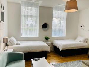 una camera con due letti, un divano e una sedia di Midland Apartment- Studio a Leicester