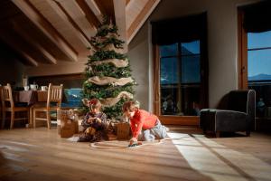 a woman sitting in a living room next to a christmas tree at Agriturismo Rini in Bormio