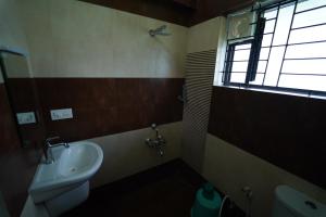 a bathroom with a sink and a toilet and a window at Vrindhavan Mist City Resorts in Kanthalloor