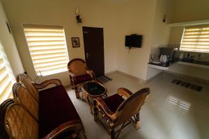 a living room with chairs and a table and a tv at Vrindhavan Mist City Resorts in Kanthalloor
