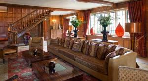 a living room with a couch and a staircase at Whatley Manor in Malmesbury