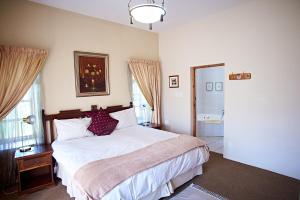 a bedroom with a large bed and a bathroom at Lake Clarens Guest House in Clarens
